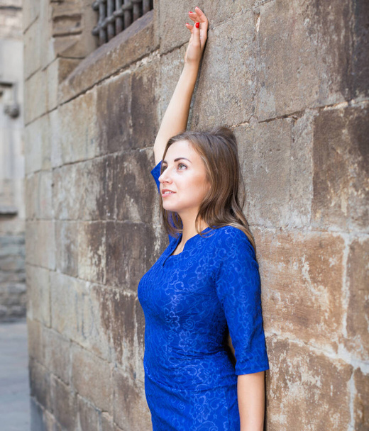 Cheerful female is playfully posing in blue dress near wall - Fotoğraf, Görsel