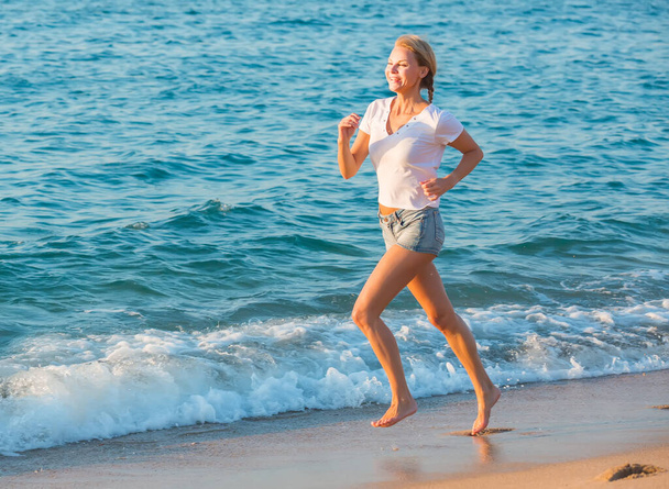 Female in white T-shirt is jogging - Фото, изображение