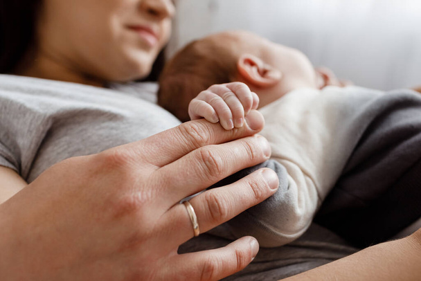 Küçük bir bebek eli tutan genç ebeveynler. Anneye, babaya ve bebek ellerine yakın çekim, kırpılmış atış. Çocuk bakımı, aile. - Fotoğraf, Görsel