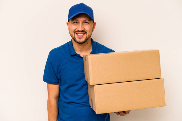 Hispanic delivery man isolated on white background laughing and having fun. - Photo, Image