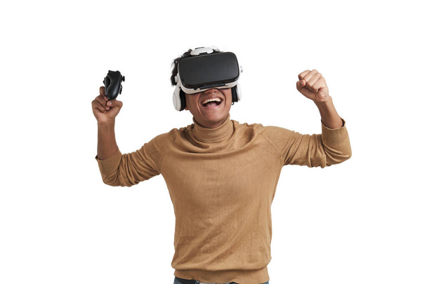 Young peruvian man playing games with joystick and vr headset, isolated. - Foto, Bild