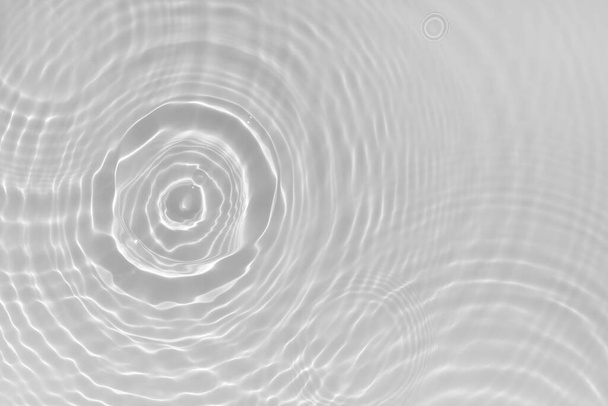 Waterstructuur met zonnereflecties en watercirkels op het wateroppervlak. Overlay effect voor foto of mockup. Organisch lichtgrijs druppel schaduw bijtende effect breking van het licht. Banner met kopieerruimte - Foto, afbeelding