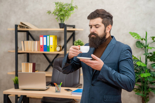 handsome brutal ceo in businesslike suit has lunch break with coffee cup at the office, morning - Zdjęcie, obraz