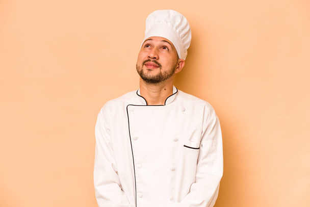 Hispanic kokki mies eristetty beige tausta haaveilee tavoitteiden saavuttamiseksi ja tarkoituksiin - Valokuva, kuva