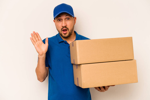 Hispanic delivery man isolated on white background surprised and shocked. - Foto, imagen