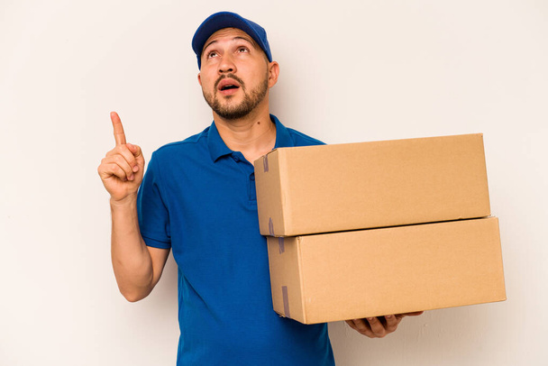 Hispanic delivery man isolated on white background pointing upside with opened mouth. - Photo, Image