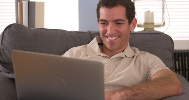 Mutlu adam kanepede dizüstü bilgisayar kullanarak - Fotoğraf, Görsel