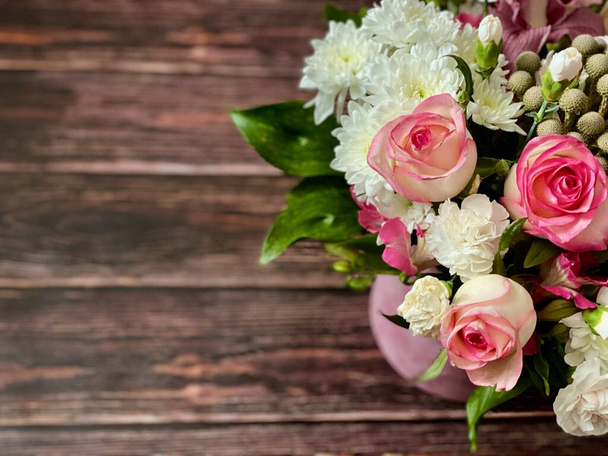 木製の背景に美しいバラ、ヴィンテージ木製の表面、木製の茶色のテクスチャの背景に丸い箱の中に異なる花を持つ美しい花束。挨拶や招待状の概念。ありがとうカードコピースペース - 写真・画像