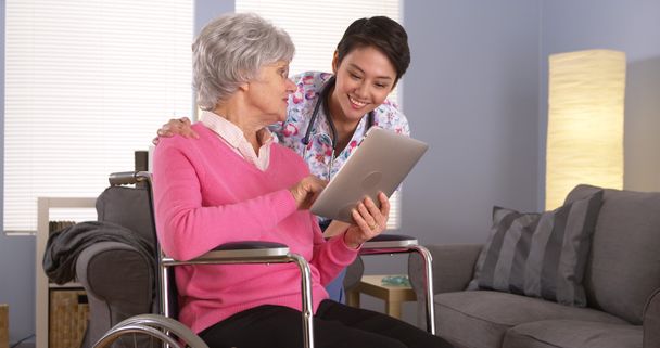 Китаянка и пожилая пациентка разговаривают с планшетом
 - Фото, изображение