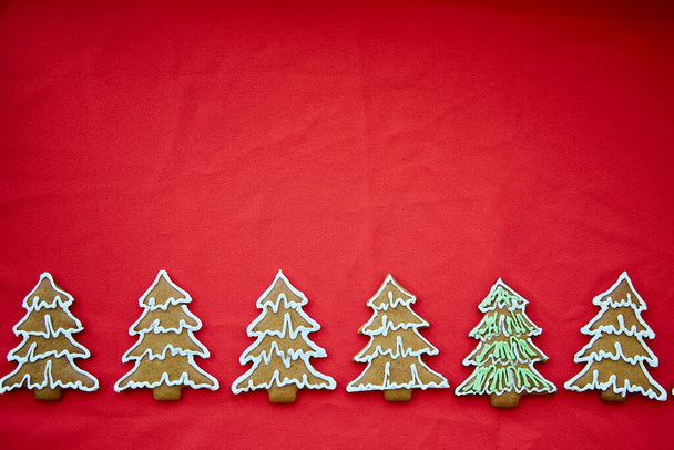 Kırmızı kumaş kaplamalı el yapımı zencefilli kurabiyeler. Noel ağacı kurabiyeleri. Minimalist Noel atmosferli bir kutlama kartı. Mutlu Noeller ve ev konforu. - Fotoğraf, Görsel