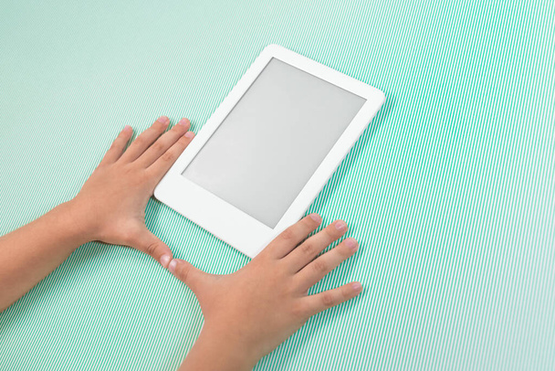 Ebook reader over groene achtergrond - wordt vastgehouden door de hand van een kind - Foto, afbeelding