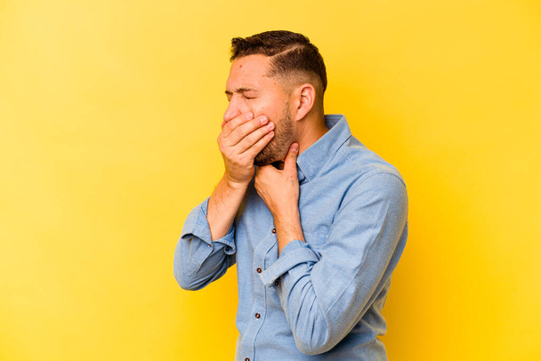 Young hispanic man isolated on yellow background suffers pain in throat due a virus or infection. - Фото, изображение