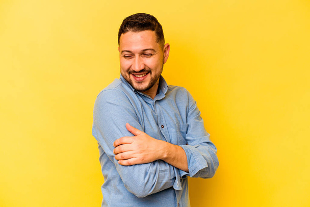 Fiatal spanyol férfi elszigetelt sárga háttér nevetés és szórakozás. - Fotó, kép