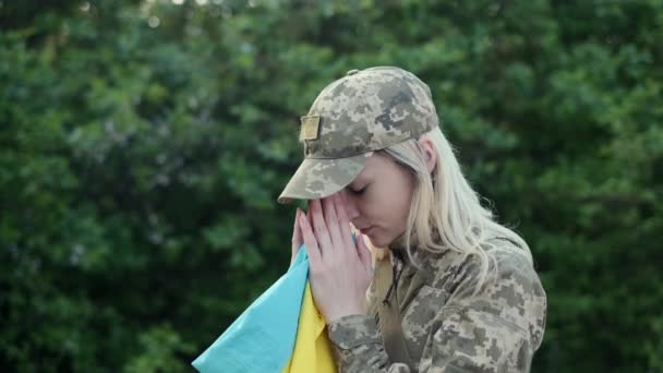 Female patriot soldier holds Ukrainian flag and praying with hope - Filmagem, Vídeo
