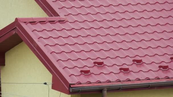 Osłona przeciwśnieżna zimą na dachu domu pokryta stalowymi gontami. Pokrycie okładziną budynku - Materiał filmowy, wideo