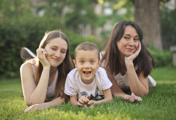 family consisting of mother and two children lying on a lawn - Photo, Image