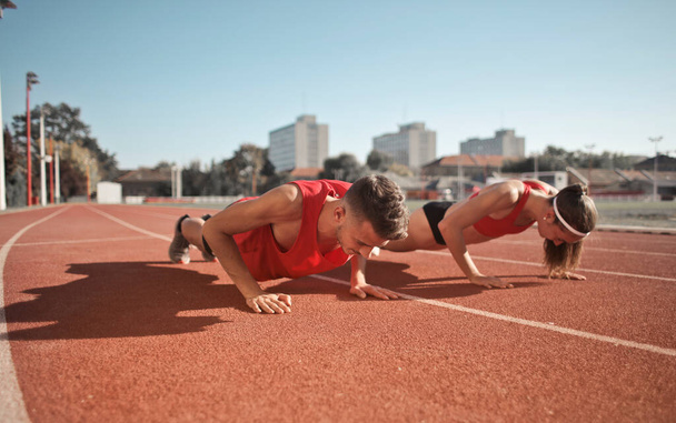 two young boys do push-ups to train on a track - Valokuva, kuva