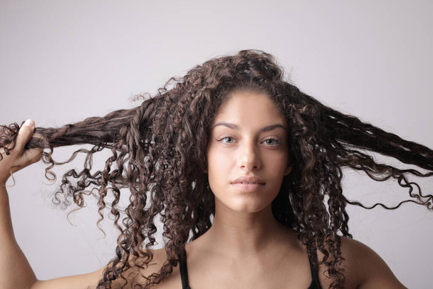 portrait of young woman touching her wavy hair - Foto, Bild