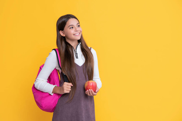 niño positivo con mochila escolar y manzana sobre fondo amarillo - Foto, imagen