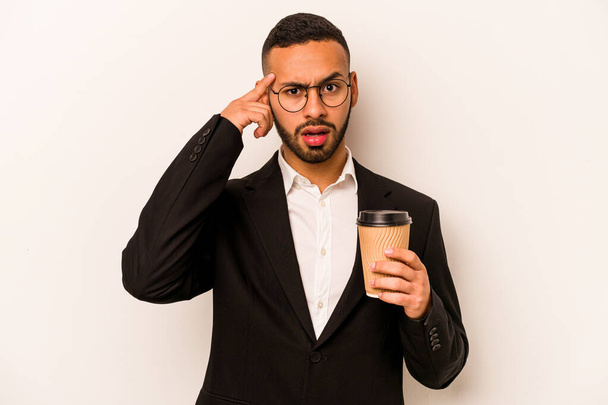 Junger hispanischer Geschäftsmann hält Kaffee zum Mitnehmen isoliert auf weißem Hintergrund und zeigt eine enttäuschende Geste mit dem Zeigefinger. - Foto, Bild