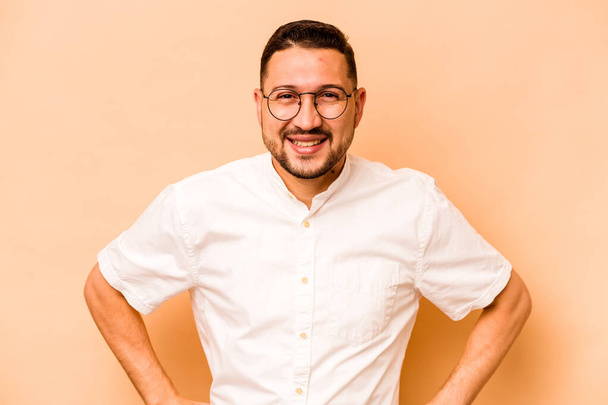 Young hispanic man isolated on beige background happy, smiling and cheerful. - Photo, Image