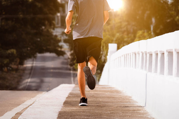 Jongeman runner voeten lopen op de brug weg van de stad te rennen voor oefening. gezond oefenconcept. - Foto, afbeelding