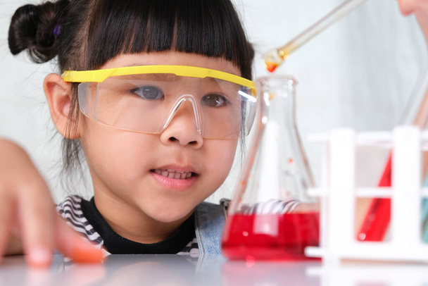 Kinderen leren en doen wetenschappelijke experimenten in de klas. Meisje speelt wetenschappelijk experiment voor thuisonderwijs. Eenvoudige en leuke wetenschappelijke experimenten voor kinderen thuis. - Foto, afbeelding
