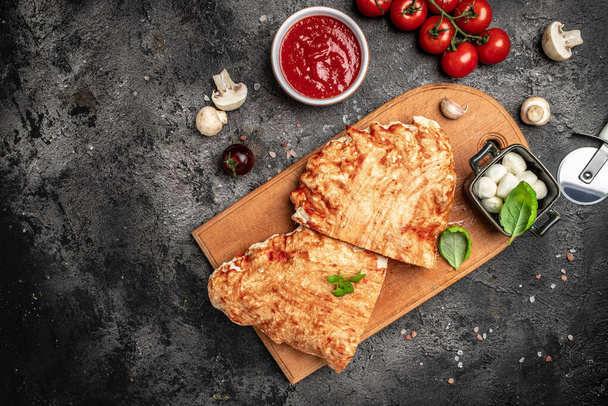 Calzone pizza with tomatoes, mozzarella, mushrooms and fresh basil, italian calzone vegetarian pizza, Food recipe background. Close up, - 写真・画像