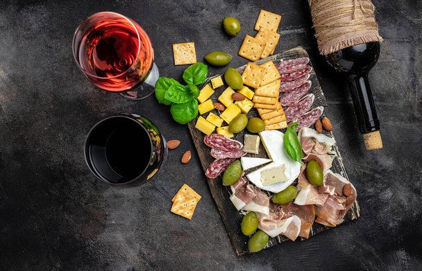 Antipasto board with sliced meat, ham, salami, cheese, olives and wine on a dark background, Top view, - Fotoğraf, Görsel
