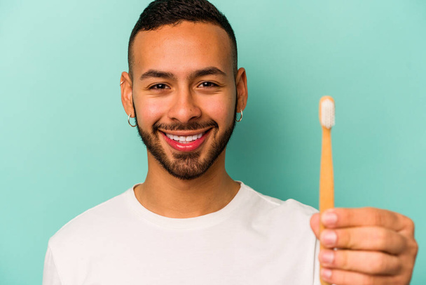 Young hispanic man wearing a toothbrush isolated on blue background - Fotoğraf, Görsel