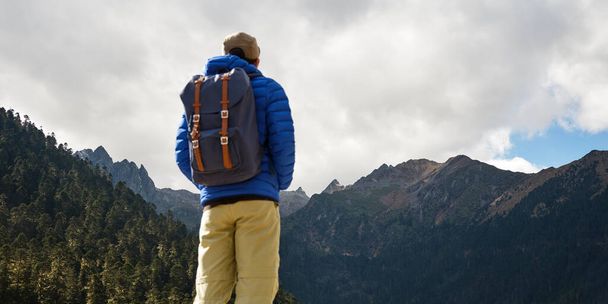 Rückansicht eines asiatischen Reisenden mit Rucksack mit Blick auf die Berge - Foto, Bild