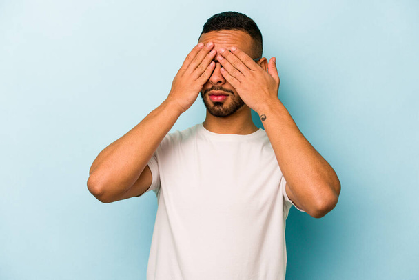 Young hispanic man isolated on blue background afraid covering eyes with hands. - Photo, Image
