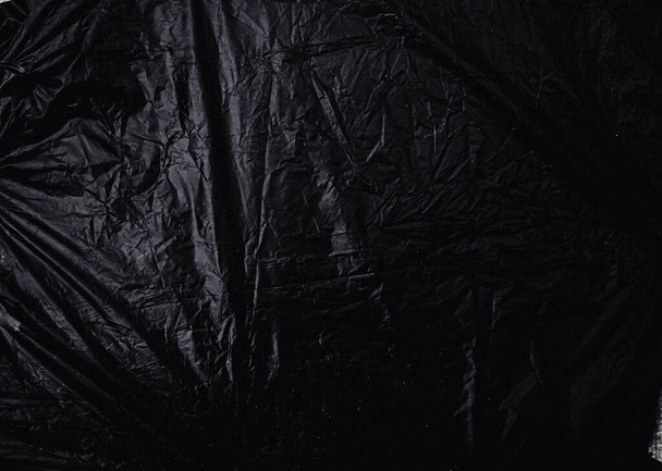 a transparent stretch plastic wrap on black background. realistic plastic wrap texture for overlay and effect. wrinkled plastic pattern for creative and decorative design. - Foto, afbeelding