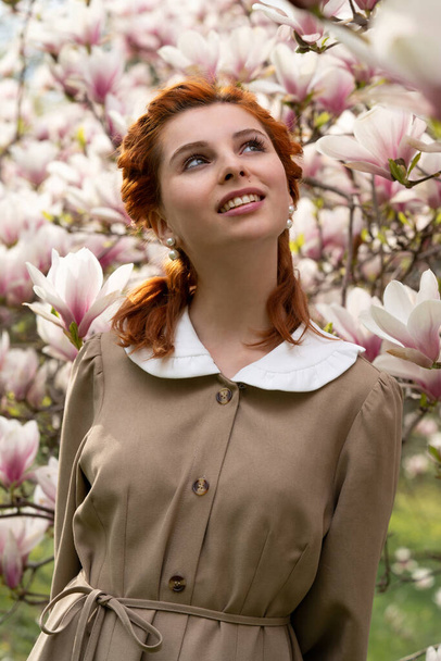 Beautiful girl in luxurious magnolia flowers. Spring in the park. Youth and teenagers. Women's fashion. Waiting for love. Charm and tenderness in the fresh air. Beautiful dress in retro style - Fotografie, Obrázek