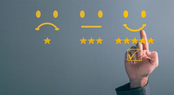Businessman's hand pressing with a checkmark on checkbox on smiley face emoticon on virtual touch screen on dark background. Customer service evaluation, client experience satisfaction surve - Photo, Image