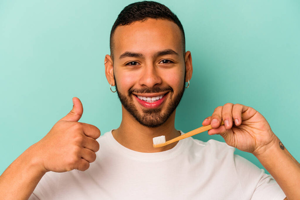 Young hispanic man wearing a toothbrush isolated on blue background - Fotografie, Obrázek