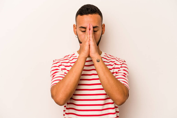 Mladý hispánec izolovaný na bílém pozadí drží ruce v modlitbě blízko úst, cítí se sebejistý. - Fotografie, Obrázek