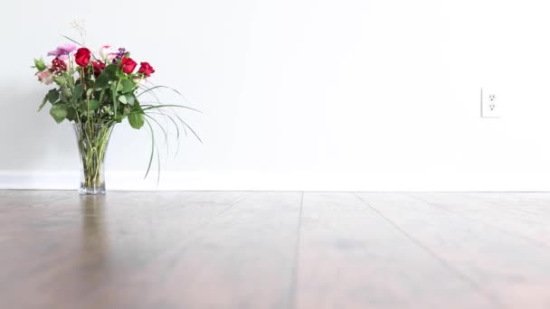 Scivolamento davanti a un vaso con bouquet di rose collocato nell'angolo di una stanza vuota con parete bianca brillante - Filmati, video