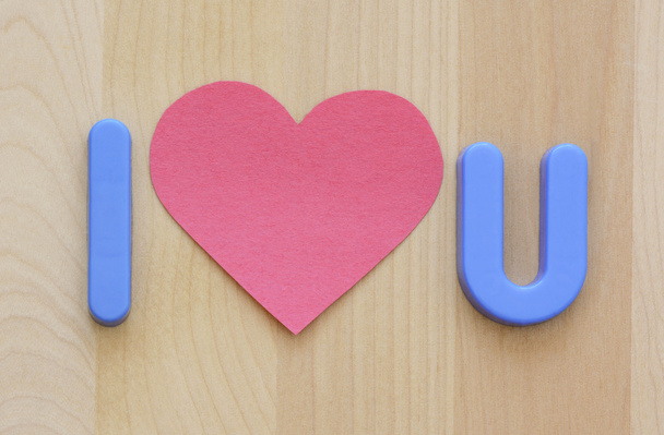 Εγώ αγαπώ U με πλαστικό παιχνίδι μπλε γράμματα και επίπεδη ροζ καρδιά σχήμα χαρτιού - Φωτογραφία, εικόνα