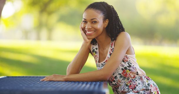 Donna nera seduta su una panchina del parco sorridente
 - Foto, immagini