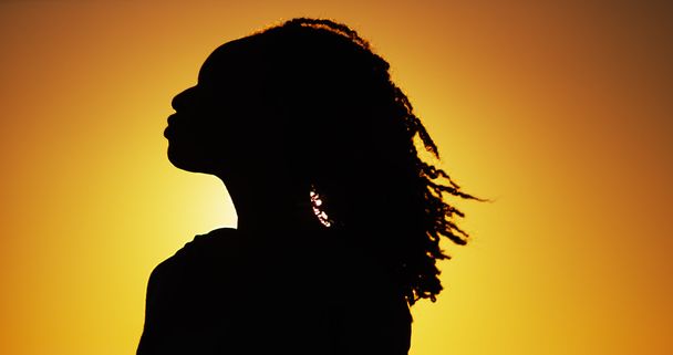 Silueta de mujer africana de pie al atardecer
 - Foto, Imagen