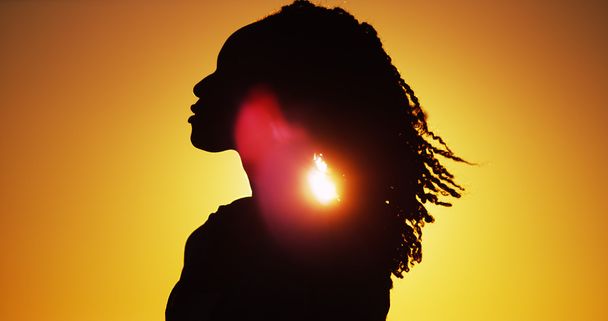 Hermosa silueta de mujer africana de pie al atardecer
 - Foto, Imagen