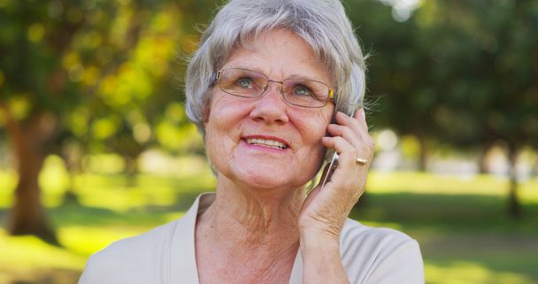 Senior woman talking on smartphone at the park - Photo, Image