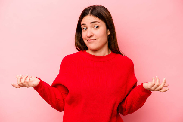 Young caucasian woman isolated on pink background doubting and shrugging shoulders in questioning gesture. - Photo, Image