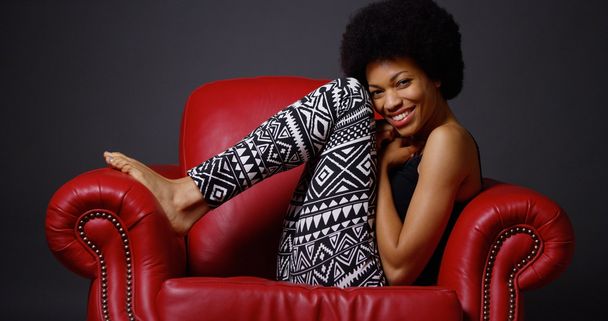 赤い肘掛け椅子に座っているアフリカの女性 - 写真・画像