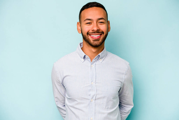 Junger hispanischer Mann isoliert auf blauem Hintergrund glücklich, lächelnd und fröhlich. - Foto, Bild