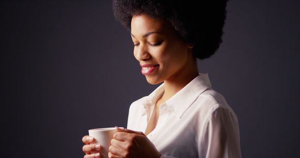 African American kobieta trzymając kubek gorącej herbaty i uśmiechając się - Zdjęcie, obraz