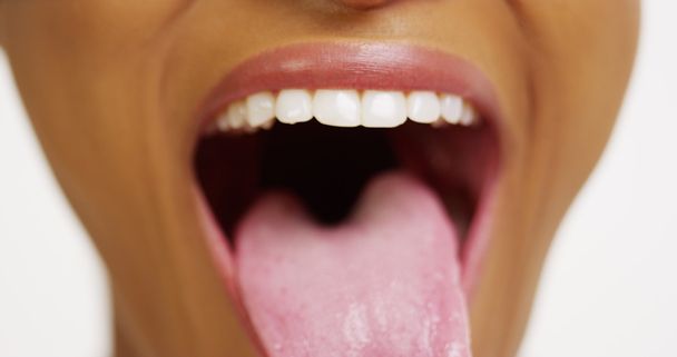 Nahaufnahme einer afrikanischen Frau mit weißen Zähnen, die lächelt und die Zunge herausstreckt - Foto, Bild
