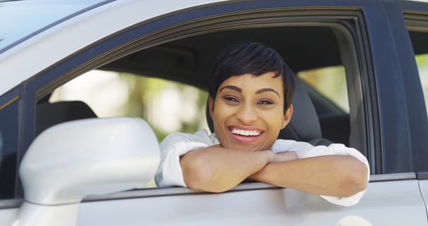 Fekete nő, és mosolyogva néz ki a kocsi ablakon - Fotó, kép