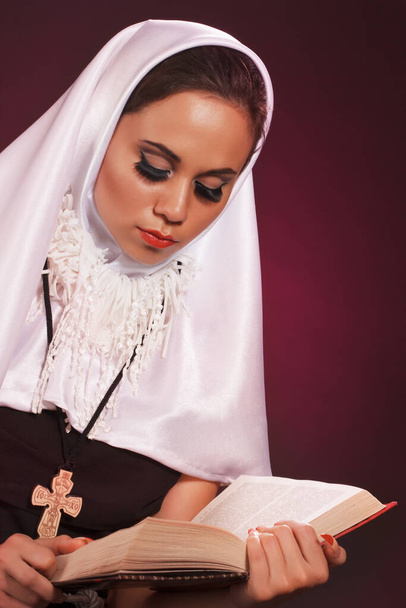 Nice girl dressed as a nun on a black background - Photo, Image